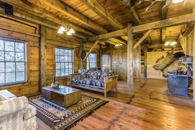 living area with wood walls, beamed ceiling, hardwood / wood-style floors, an inviting chandelier, and wood ceiling