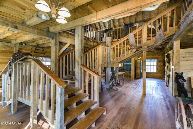 staircase featuring wood walls, beam ceiling, hardwood / wood-style floors, an inviting chandelier, and wood ceiling