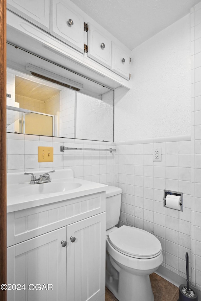 bathroom with toilet, tile patterned floors, vanity, decorative backsplash, and tile walls