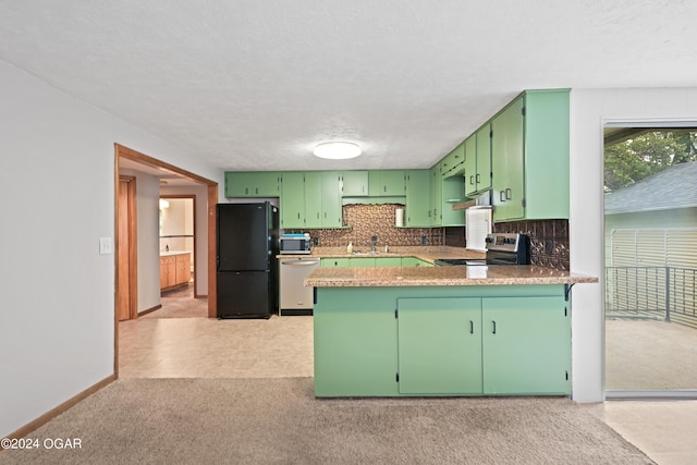 kitchen featuring appliances with stainless steel finishes, kitchen peninsula, sink, decorative backsplash, and green cabinetry