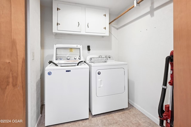 washroom with washer and clothes dryer, light tile patterned floors, and cabinets