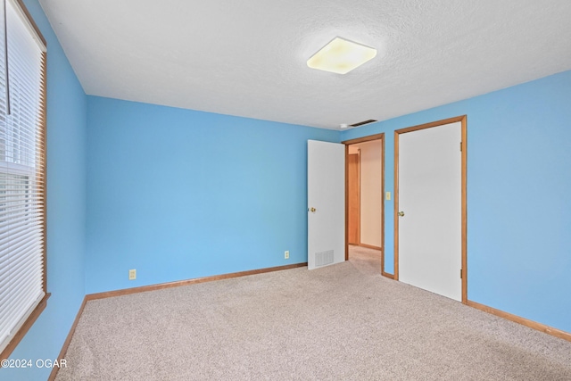 unfurnished bedroom featuring a textured ceiling, carpet flooring, and a closet