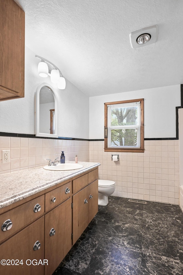 bathroom featuring tile walls, toilet, a textured ceiling, and vanity