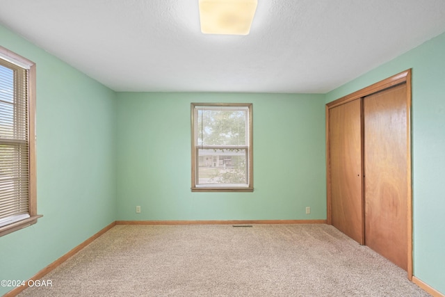 unfurnished bedroom featuring carpet flooring, a closet, and multiple windows