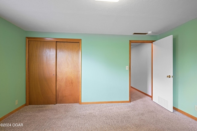 unfurnished bedroom featuring a closet and light colored carpet