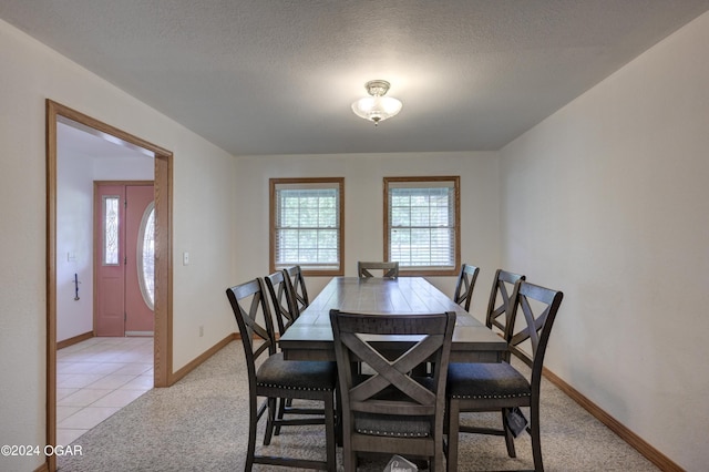 dining space with light carpet, light tile patterned floors, baseboards, and a textured ceiling