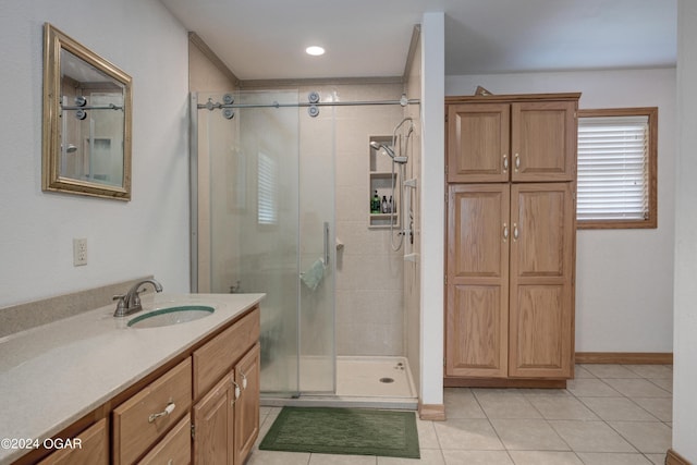 full bath featuring a stall shower, tile patterned flooring, vanity, and baseboards