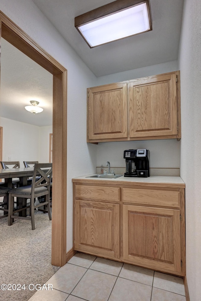 kitchen with light brown cabinetry, light countertops, a sink, and light tile patterned floors