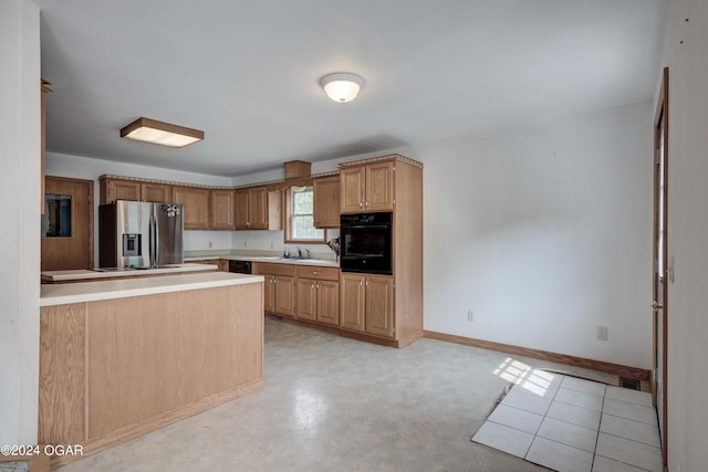 kitchen with finished concrete flooring, light countertops, a sink, black appliances, and baseboards