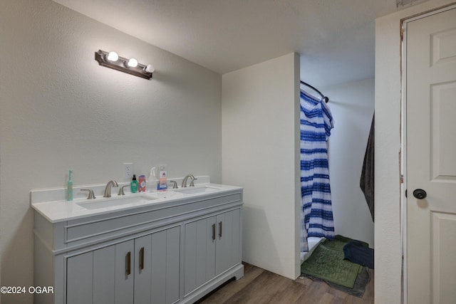 bathroom with double vanity, wood finished floors, a shower with shower curtain, and a sink