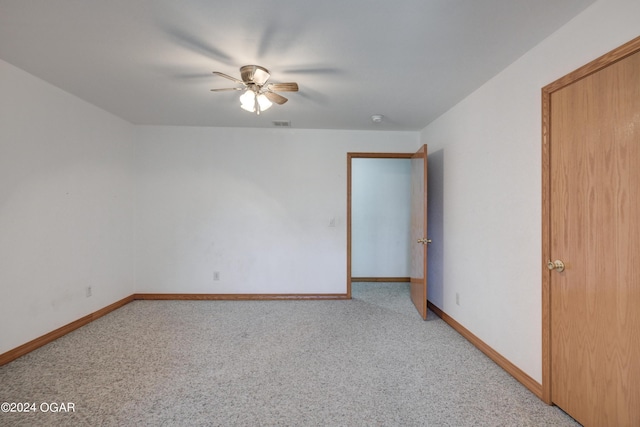 spare room with baseboards, visible vents, a ceiling fan, and light colored carpet