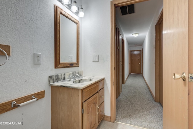 bathroom featuring visible vents, a textured wall, vanity, and baseboards