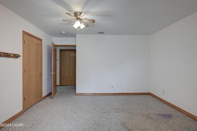 carpeted spare room with a ceiling fan, visible vents, and baseboards