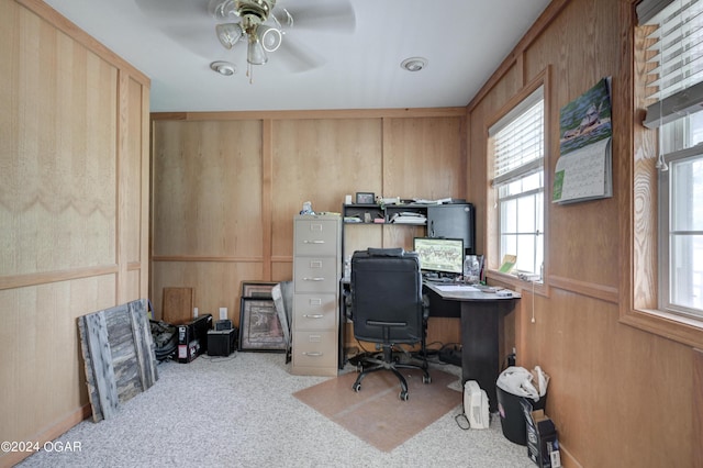 home office featuring ceiling fan, wood walls, and carpet flooring