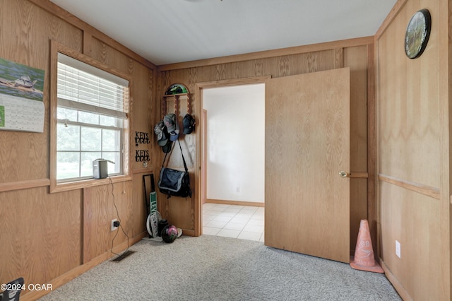 empty room featuring carpet floors, wooden walls, visible vents, and tile patterned floors