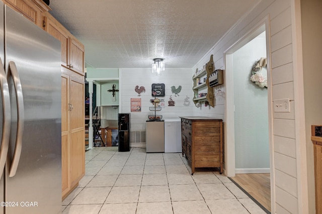 kitchen with light tile patterned floors and stainless steel fridge