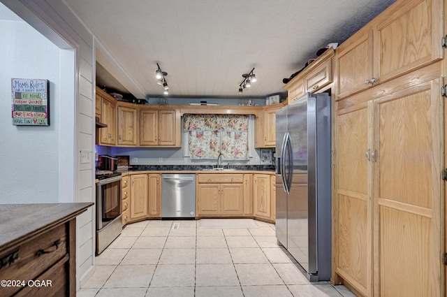 kitchen featuring rail lighting, stainless steel appliances, light tile patterned flooring, sink, and light brown cabinets