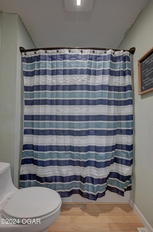 bathroom featuring toilet, hardwood / wood-style floors, and walk in shower