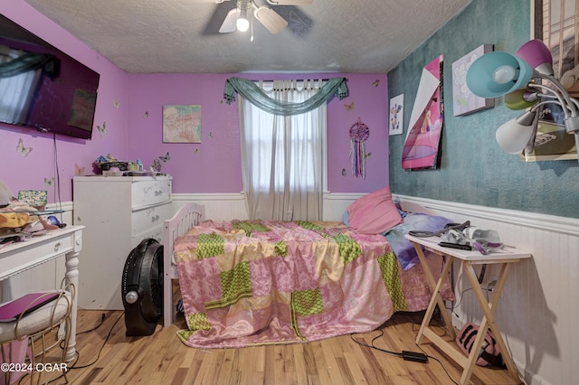 bedroom featuring ceiling fan, hardwood / wood-style flooring, and a textured ceiling