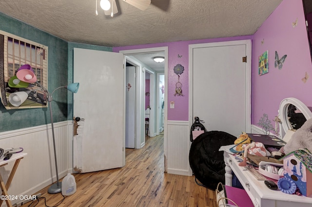 bedroom featuring ceiling fan, light hardwood / wood-style floors, and a textured ceiling