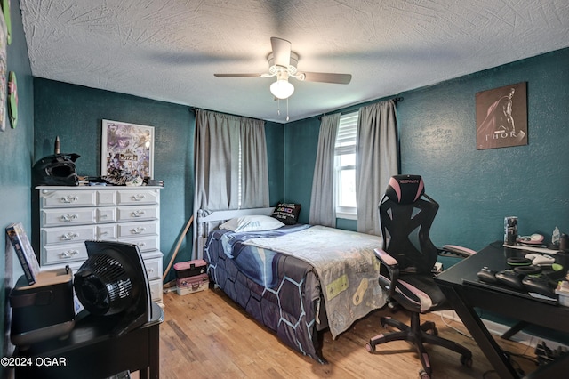 bedroom with light wood-type flooring, ceiling fan, and a textured ceiling