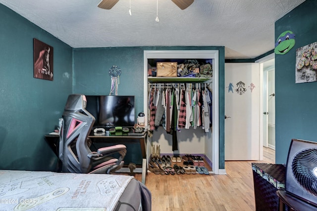 bedroom with a textured ceiling, light hardwood / wood-style flooring, ceiling fan, and a closet