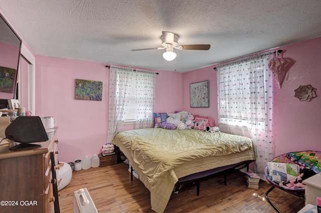 bedroom featuring a textured ceiling, ceiling fan, and light hardwood / wood-style floors