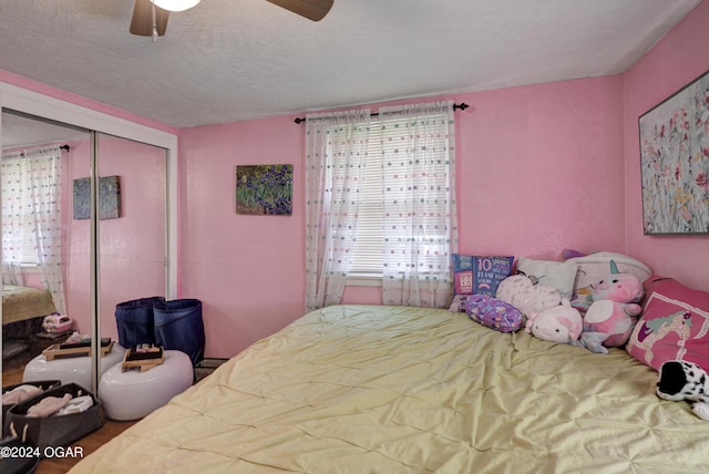 bedroom with a textured ceiling, ceiling fan, a closet, and multiple windows