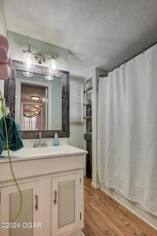 bathroom with a textured ceiling, vanity, hardwood / wood-style floors, and shower / bath combo