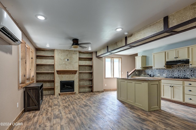 kitchen featuring a large fireplace, black gas stovetop, dark hardwood / wood-style floors, ceiling fan, and an AC wall unit