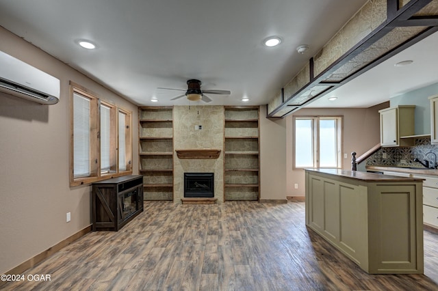 interior space featuring a wall mounted AC, dark wood-type flooring, ceiling fan, and a large fireplace