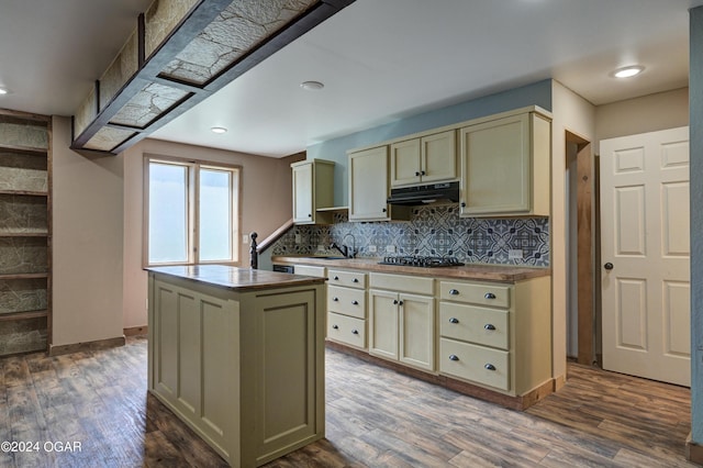 kitchen featuring cream cabinetry, tasteful backsplash, a kitchen island, dark hardwood / wood-style floors, and black gas stovetop