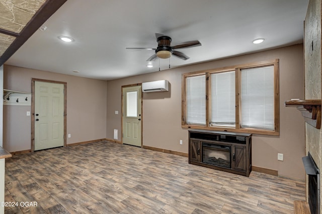 unfurnished living room featuring ceiling fan, a wall unit AC, and light wood-type flooring