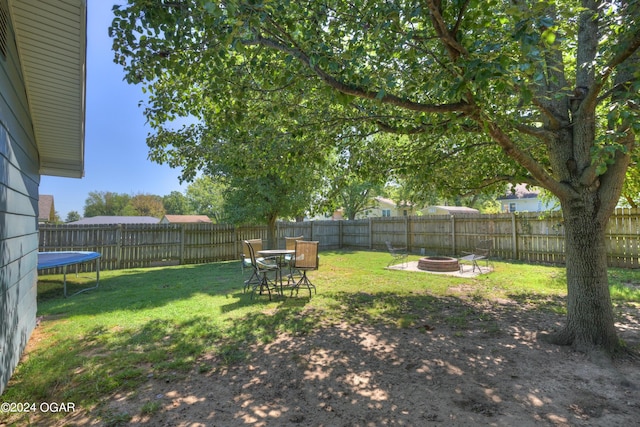 view of yard with an outdoor fire pit and a trampoline