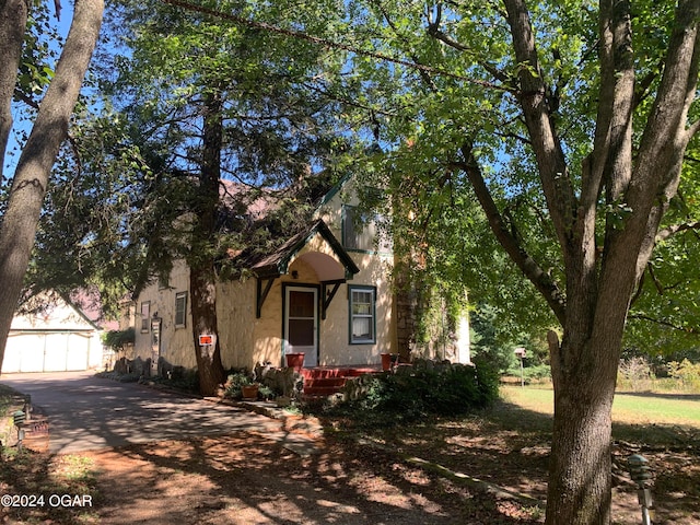 view of property hidden behind natural elements with a garage and an outbuilding