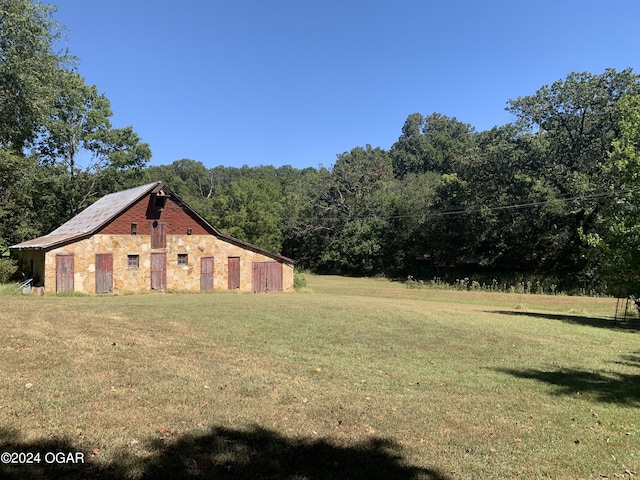 view of yard with an outbuilding and a view of trees