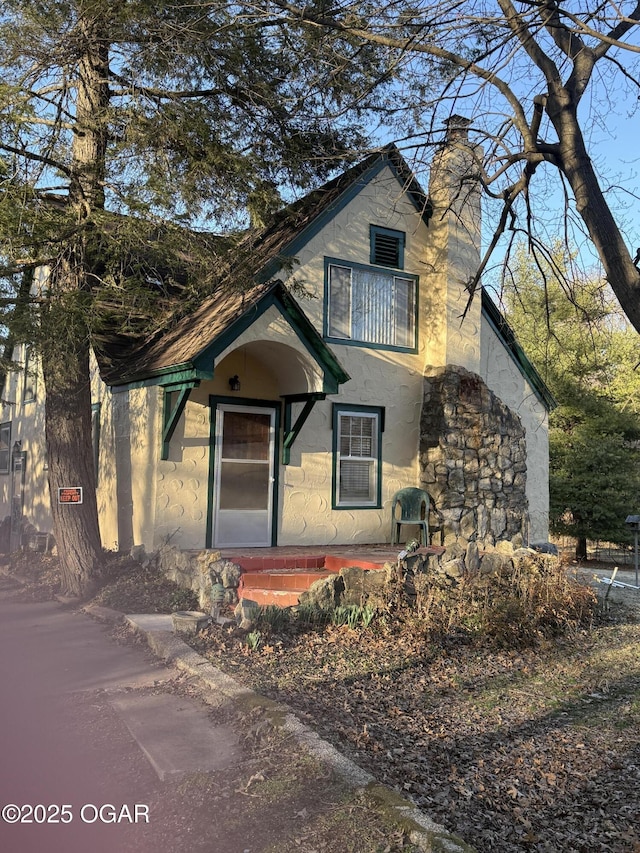 view of front of house with a balcony, a chimney, and stucco siding