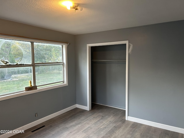 unfurnished bedroom with a closet, a textured ceiling, and hardwood / wood-style flooring