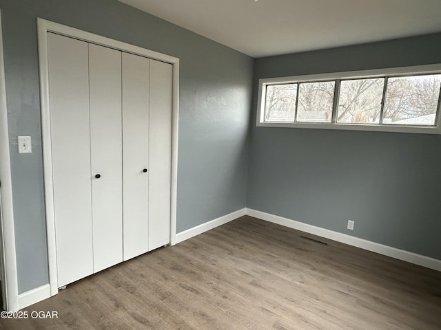 unfurnished bedroom featuring a closet, baseboards, and wood finished floors