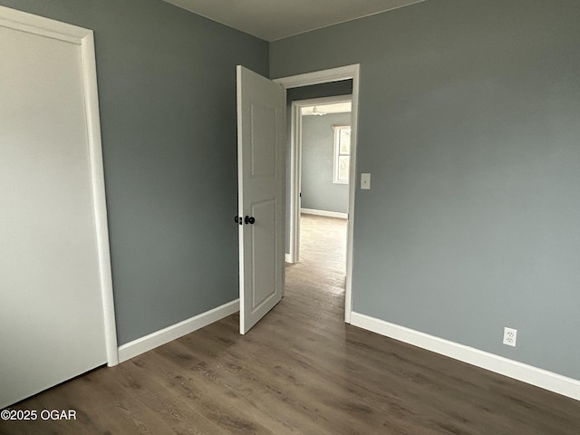 empty room featuring baseboards and dark wood-style flooring