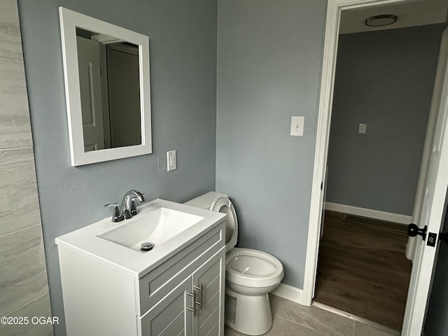 bathroom featuring toilet, tile patterned floors, baseboards, and vanity