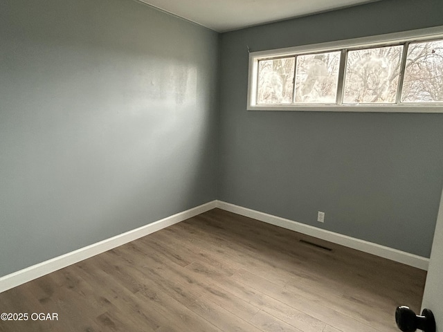 spare room featuring dark wood-type flooring and baseboards