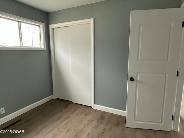 unfurnished bedroom with baseboards, a closet, and wood finished floors