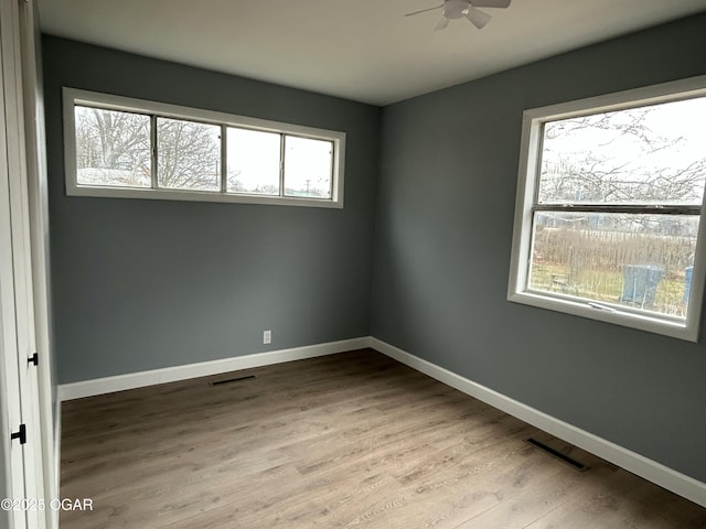 spare room featuring visible vents, ceiling fan, baseboards, and wood finished floors