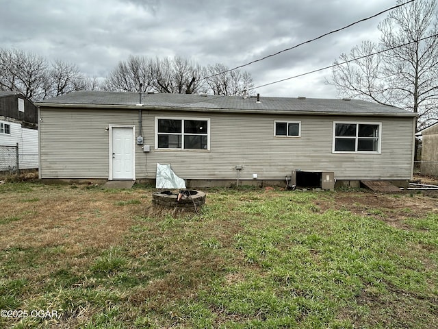 rear view of house featuring cooling unit, a yard, and an outdoor fire pit