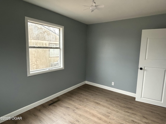 unfurnished room with a ceiling fan, baseboards, visible vents, and wood finished floors