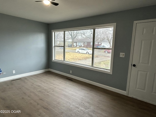 spare room featuring visible vents, wood finished floors, a ceiling fan, and baseboards