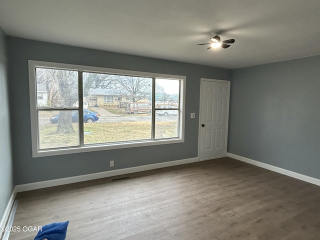 spare room with baseboards and wood finished floors