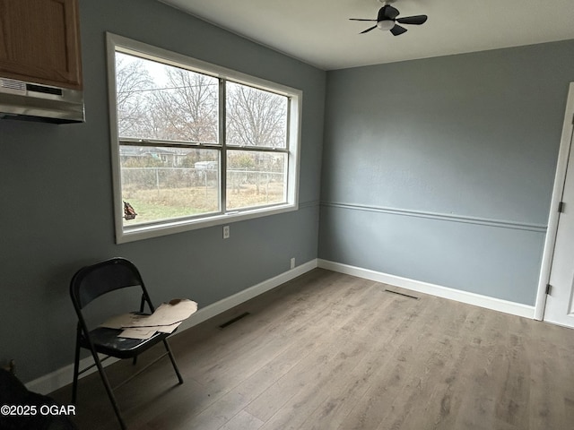 unfurnished room featuring a ceiling fan, wood finished floors, visible vents, and baseboards