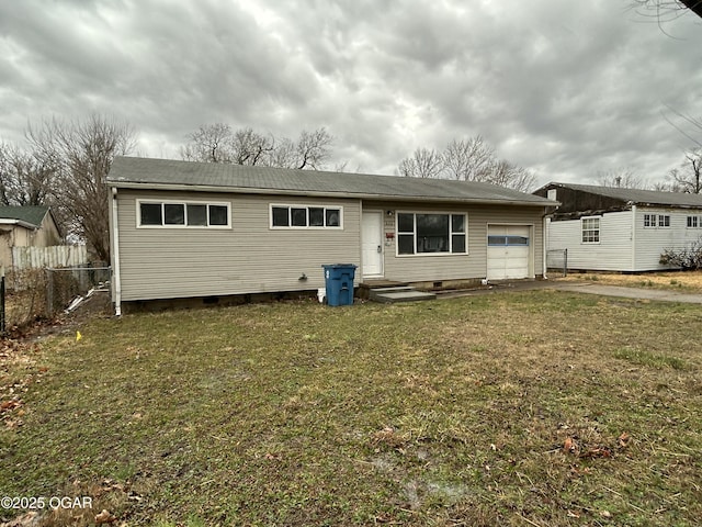 back of property featuring driveway, a garage, crawl space, fence, and a yard